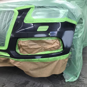 Abgeklebte Autostoßstange beim Lackieren in der Werkstatt, Reparaturarbeiten