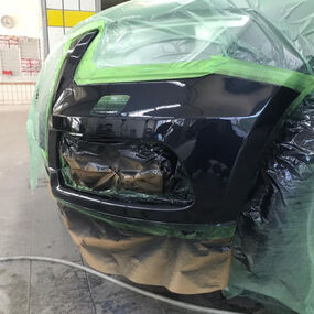 Abgeklebte Stoßstange beim Autolackieren in der Werkstatt, schwarz glänzend