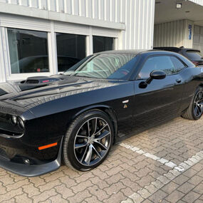 Schwarzes Dodge Challenger Muscle Car vor Werkstatt, Seitenansicht außen