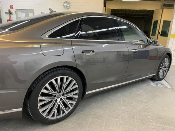 Graue Audi Limousine in Werkstatt, Seitenansicht mit Alufelgen und Lackpflege