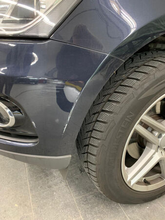 Kratzer am vorderen Kotflügel eines Autos nahe Rad und Stoßfänger, Lackschaden