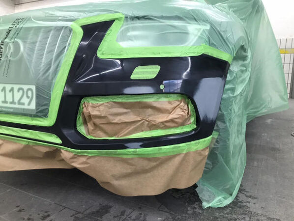 Abgeklebte Autostoßstange beim Lackieren in der Werkstatt, Reparaturarbeiten