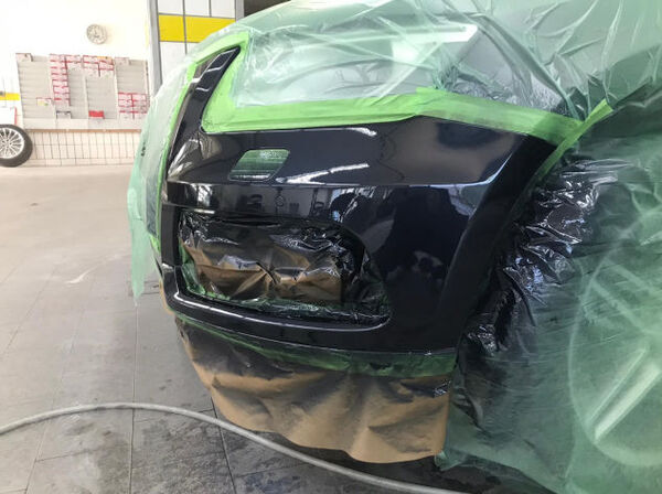 Abgeklebte Stoßstange beim Autolackieren in der Werkstatt, schwarz glänzend